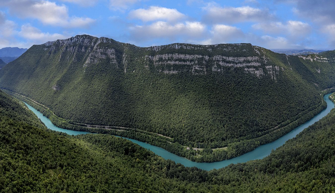 Turkizna reka Soča, ki vijuga med Sveto Goro in Sabotinom, obdana z bujno naravo in slikovitimi razgledi.