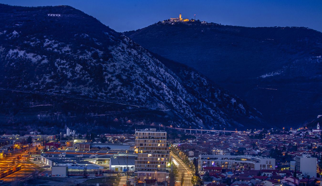 Večerni pogled na mesto Nova Gorica, v ozadju osvetljena Sveta Gora