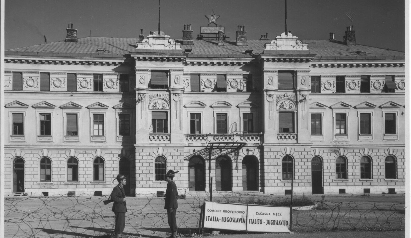 Gorica - železniška postaja v obdobju med letom 1948 in 1955, na sliki sta dva vojak na meji ob bodeči žici, poleg je tabla z napisom Italija-Jugoslavija