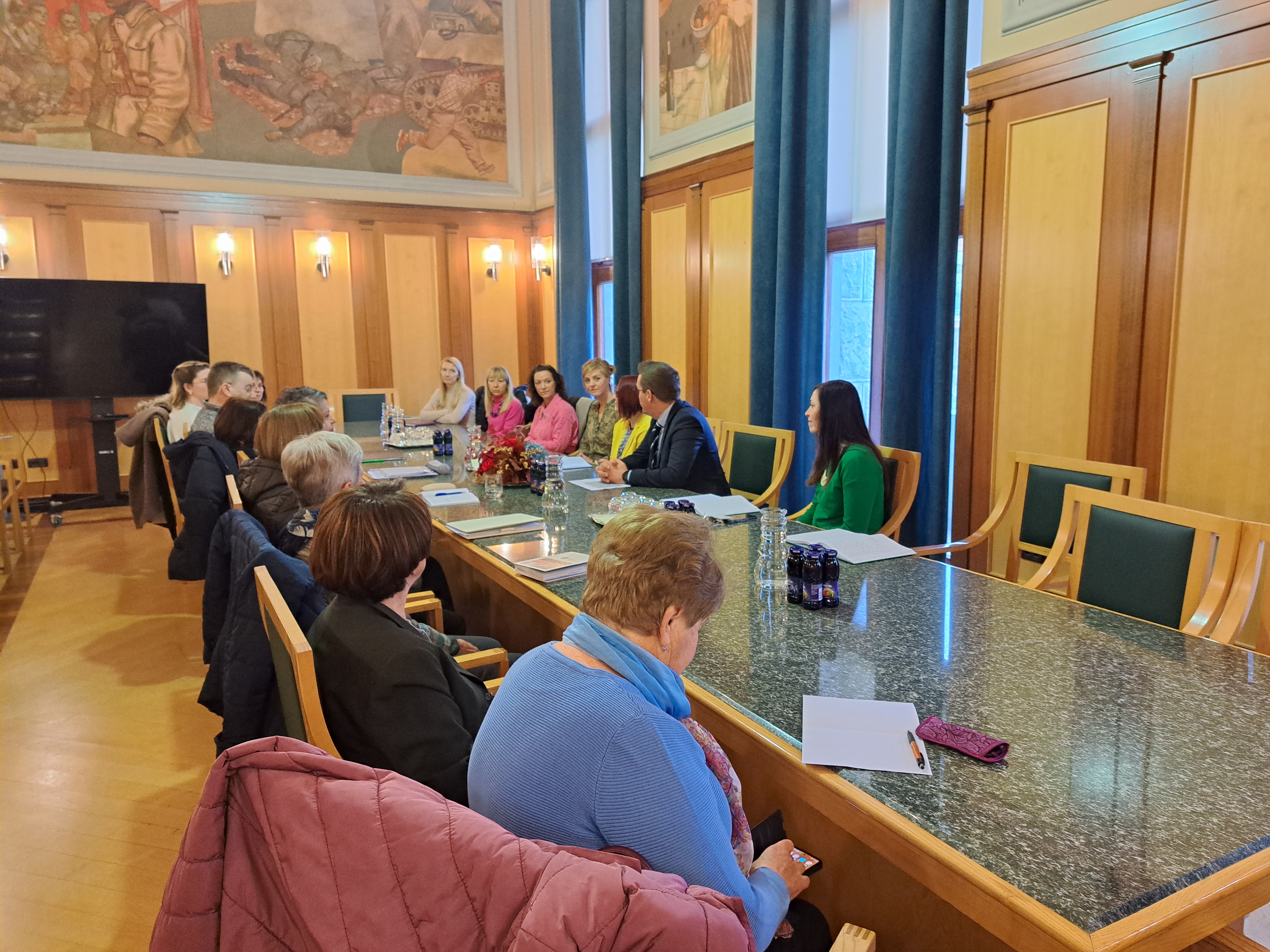 Predstavniki društev kroničnih bolnikov sedijo za mizo z novogoriškim županom Samom Turelom v zeleni dvorani občinske stavbe