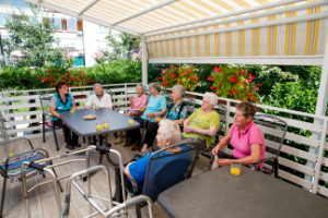 Starejši občani sedijo ob mizi na terasi Dnevnega centra
