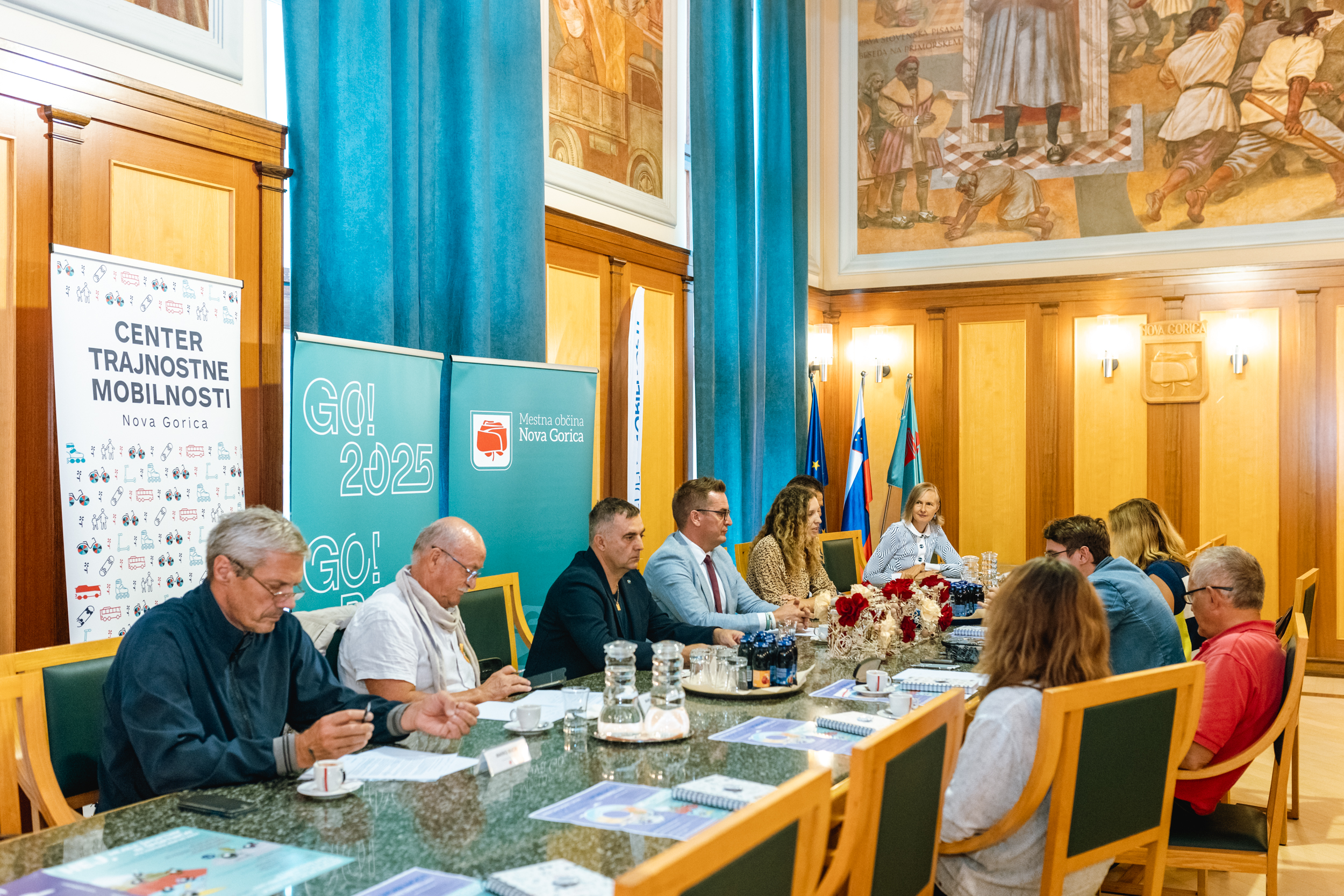 Udeleženci novinarske konference sedijo za veliko mizo v Zeleni dvorani novogoriške občinske palače.