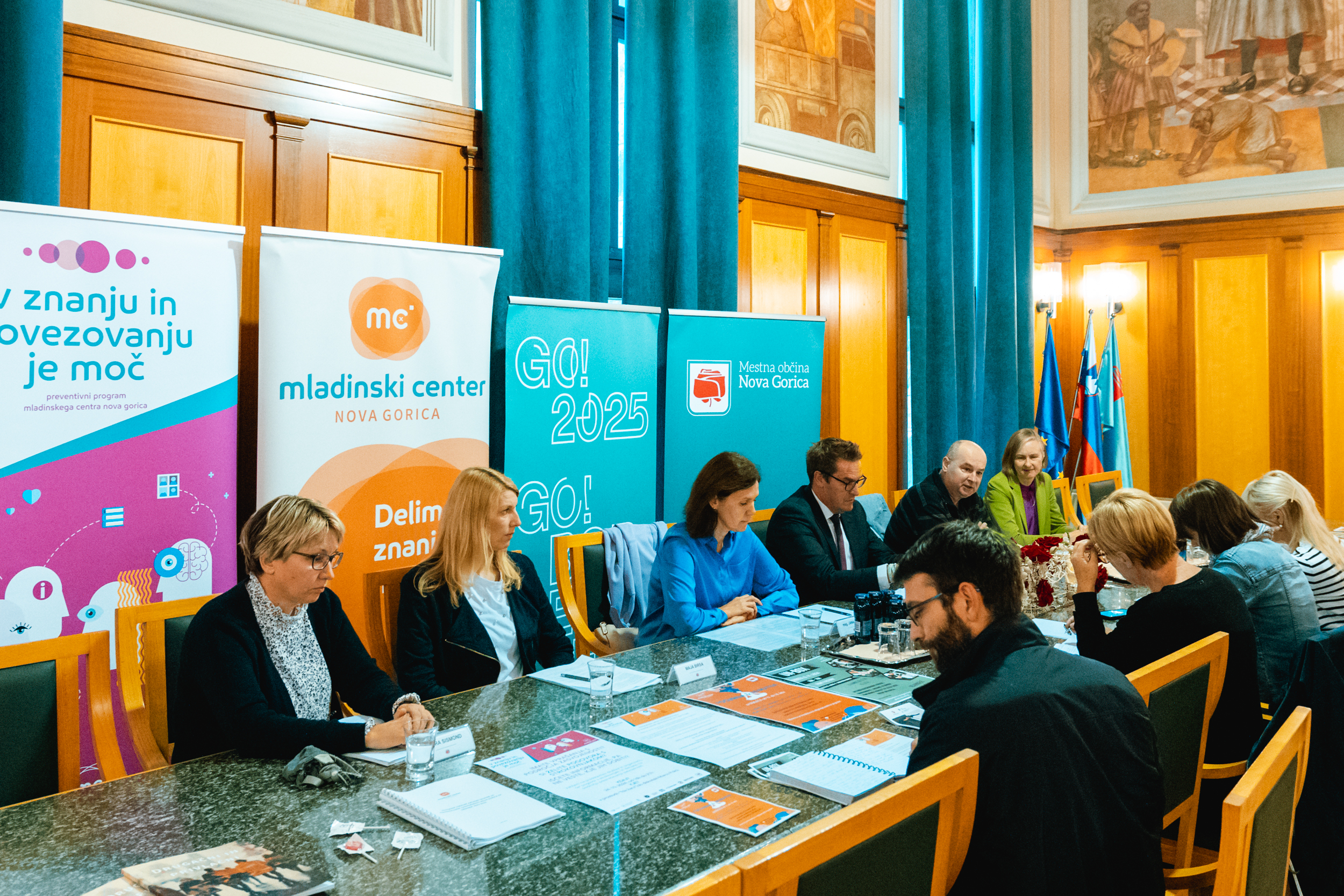 Udeleženci novinarske konference sedijo na veliko mizo v Zeleni dvorani novogoriške Občinske palače.